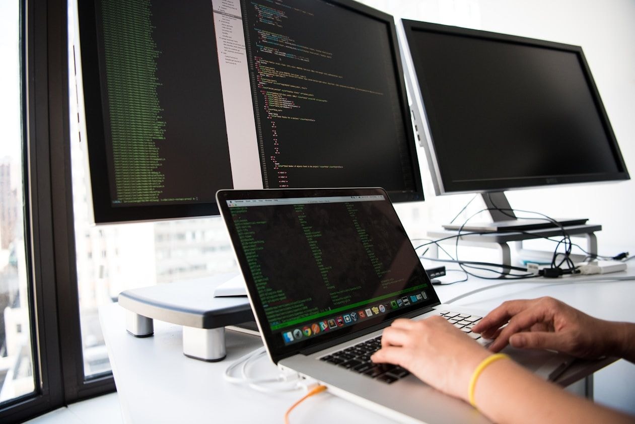 Ordinateur portable et écrans de supervision dans un environnement informatique professionnel.